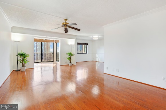 spare room with light wood-style floors, a ceiling fan, baseboards, and ornamental molding