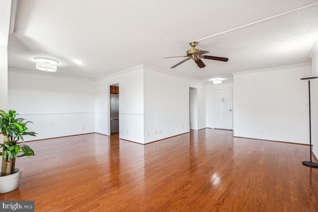 unfurnished living room with wood finished floors, crown molding, baseboards, a textured ceiling, and ceiling fan