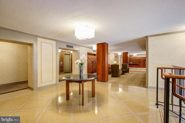 hall with baseboards, visible vents, a textured ceiling, and ornamental molding