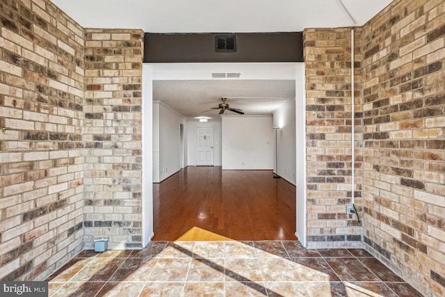 interior space featuring visible vents, crown molding, and brick wall