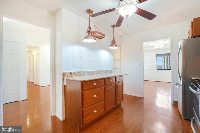 kitchen with a ceiling fan, brown cabinets, appliances with stainless steel finishes, and wood finished floors