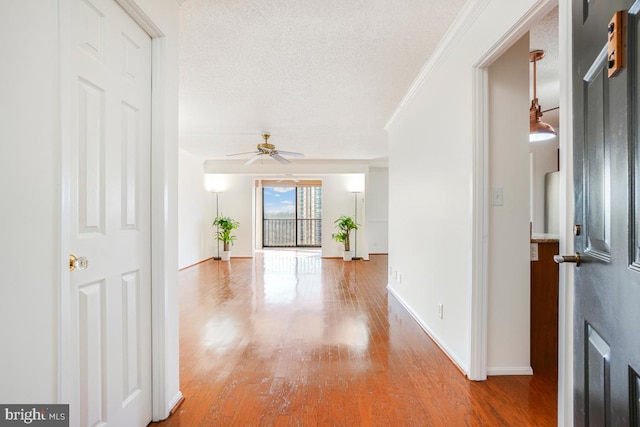 hall with wood finished floors, baseboards, and a textured ceiling