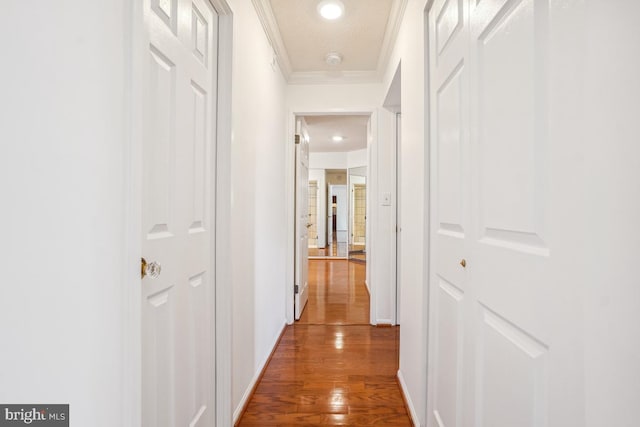 hallway with wood finished floors, baseboards, and ornamental molding