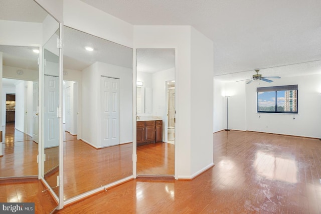 unfurnished bedroom with ensuite bath, baseboards, light wood-style floors, and a closet