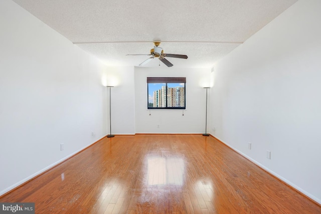 spare room featuring a ceiling fan, wood finished floors, and a textured ceiling