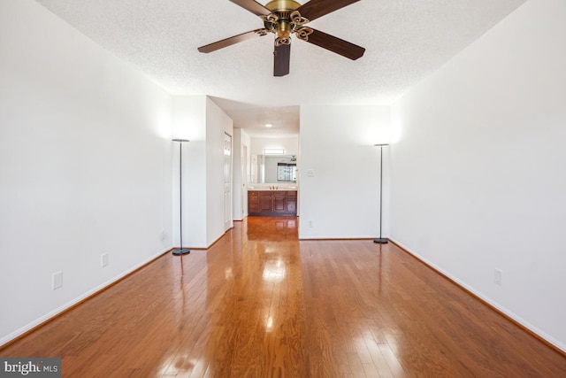 unfurnished room featuring baseboards, a ceiling fan, wood finished floors, and a textured ceiling
