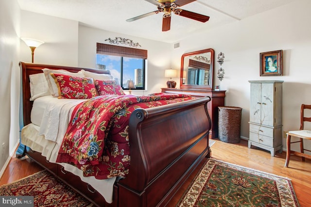 bedroom featuring wood finished floors, visible vents, baseboards, and ceiling fan