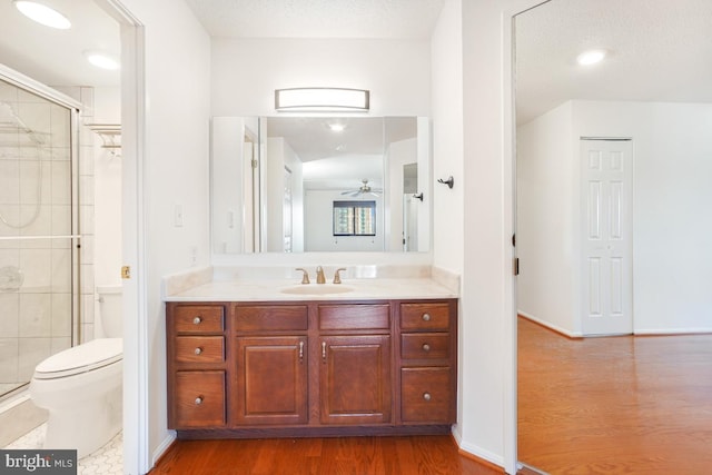 bathroom with wood finished floors, a shower stall, and toilet