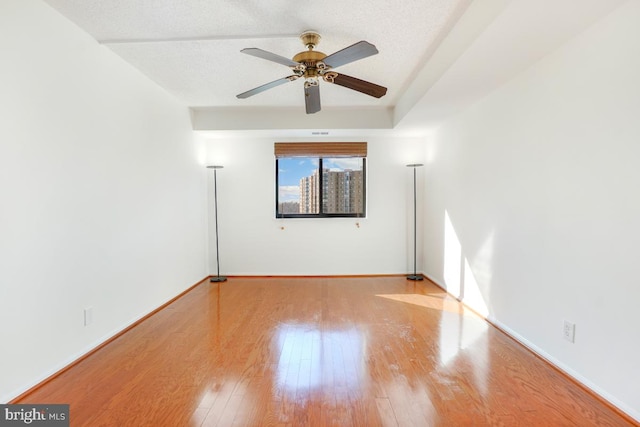 spare room with baseboards, wood finished floors, and ceiling fan