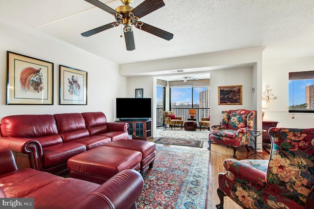 living area with wood finished floors, ceiling fan, and crown molding