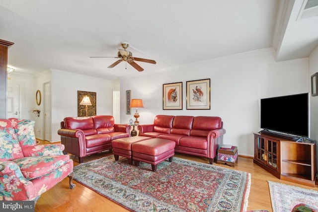 living area with ornamental molding, wood finished floors, visible vents, and ceiling fan