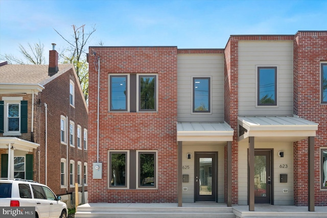 multi unit property with a standing seam roof, brick siding, and metal roof
