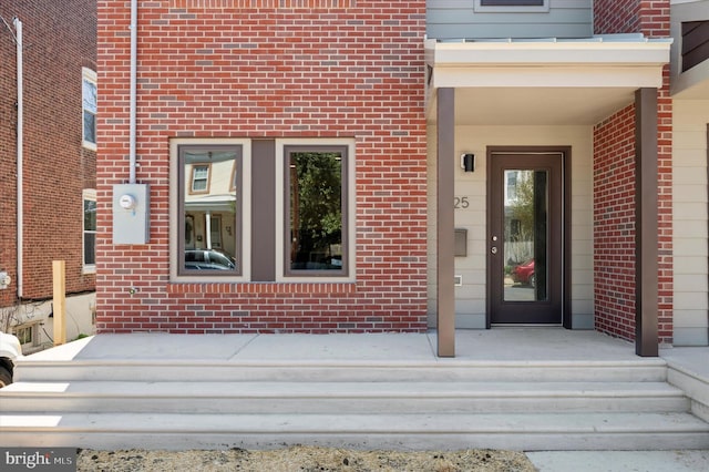 view of exterior entry featuring brick siding