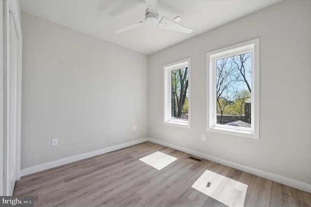 spare room featuring wood finished floors, visible vents, and baseboards