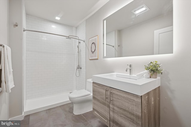 bathroom featuring a tile shower, visible vents, toilet, and vanity