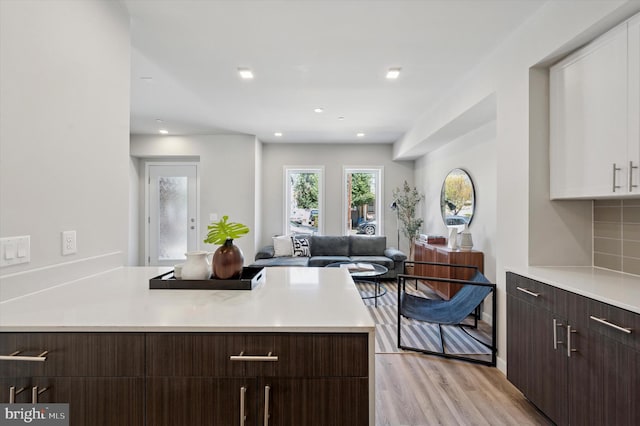 kitchen featuring white cabinets, light countertops, dark brown cabinetry, a peninsula, and light wood-style flooring