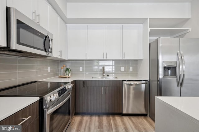 kitchen featuring stainless steel appliances, light countertops, a sink, and white cabinetry