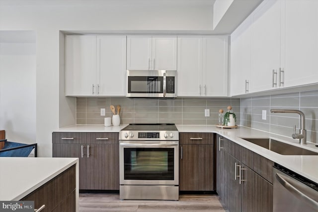 kitchen featuring white cabinets, light countertops, stainless steel appliances, and a sink