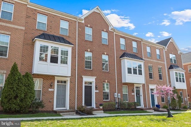 748 S Macon St, Baltimore, MD 21224 - view of property featuring brick siding, a standing seam roof, and a front yard