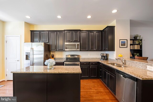 748 S Macon St, Baltimore, MD 21224 - kitchen with stainless steel appliances, a sink, light stone counters, a center island, and tasteful backsplash