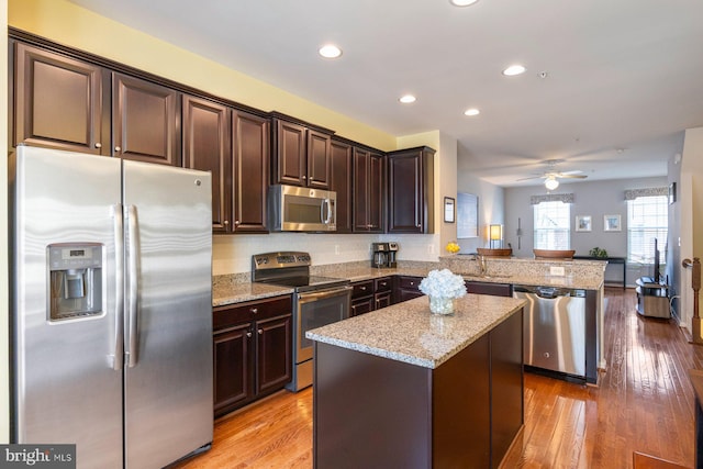 748 S Macon St, Baltimore, MD 21224 - kitchen with stainless steel appliances, a peninsula, dark brown cabinetry, light stone counters, and recessed lighting