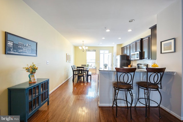 748 S Macon St, Baltimore, MD 21224 - kitchen with stainless steel appliances, a chandelier, a kitchen breakfast bar, dark wood-type flooring, and a peninsula