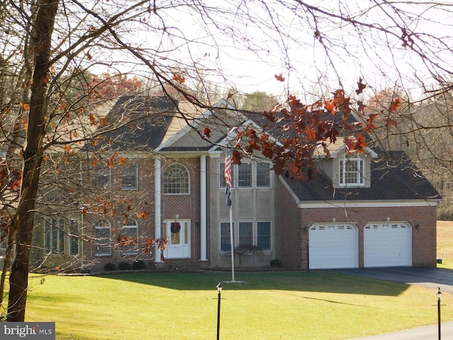 greek revival house with brick siding, a front lawn, aphalt driveway, and a garage