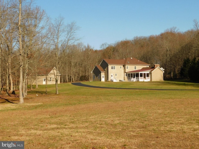 exterior space featuring a lawn, a wooded view, and stucco siding
