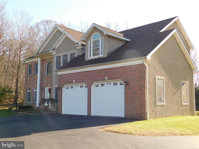 view of side of home with brick siding, an attached garage, stucco siding, and driveway
