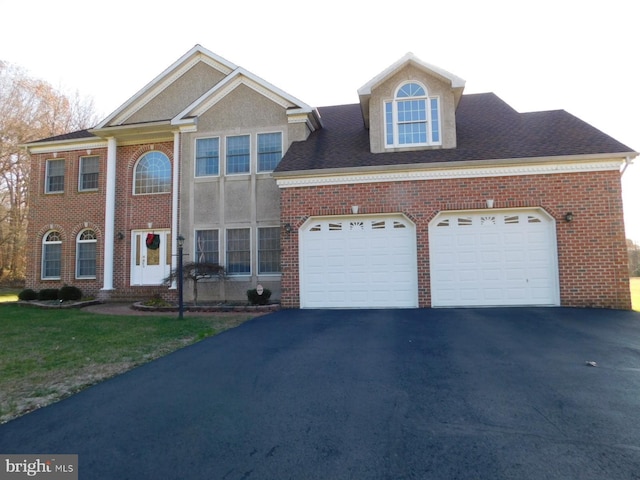 view of front facade featuring brick siding, an attached garage, a front yard, and aphalt driveway