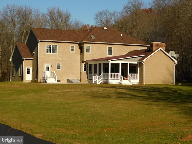 rear view of property with a sunroom, a yard, and stucco siding