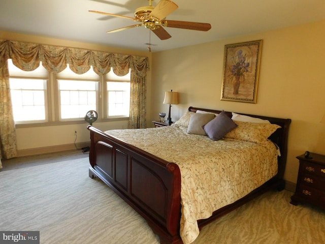 bedroom with ceiling fan, baseboards, and light colored carpet