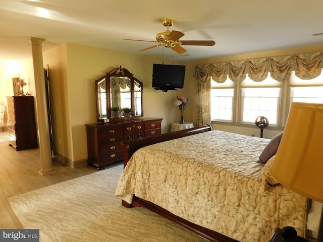 bedroom with light wood-style flooring, ornate columns, and ceiling fan