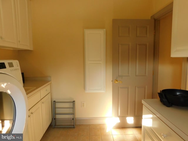 laundry area with baseboards, cabinet space, light tile patterned floors, and washer / dryer