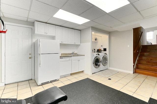 clothes washing area with washing machine and dryer, baseboards, a sink, and laundry area