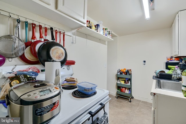 4315 Washington Blvd, Halethorpe, MD 21227 - kitchen with light tile patterned flooring, white cabinets, light countertops, a sink, and baseboards