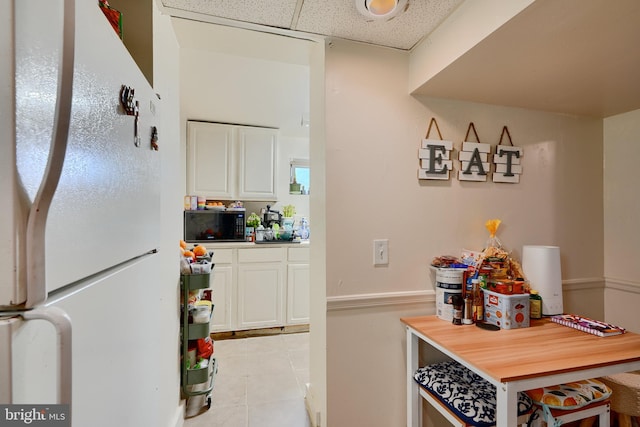 4315 Washington Blvd, Halethorpe, MD 21227 - kitchen with freestanding refrigerator, white cabinets, light tile patterned floors, and a paneled ceiling