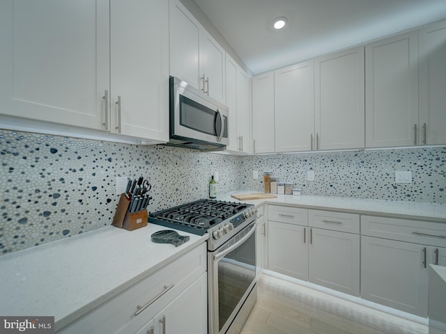 2109 M St NE Unit 5, Washington, DC 20002 - kitchen with stainless steel microwave, range with gas cooktop, backsplash, white cabinetry, and recessed lighting