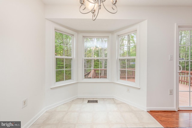 unfurnished dining area featuring visible vents, baseboards, and a notable chandelier
