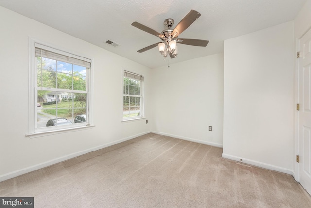 unfurnished room featuring light colored carpet, baseboards, a ceiling fan, and visible vents