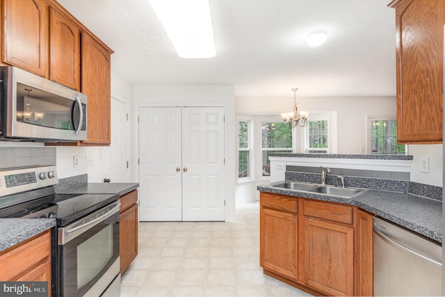kitchen featuring a sink, dark countertops, brown cabinets, light floors, and appliances with stainless steel finishes