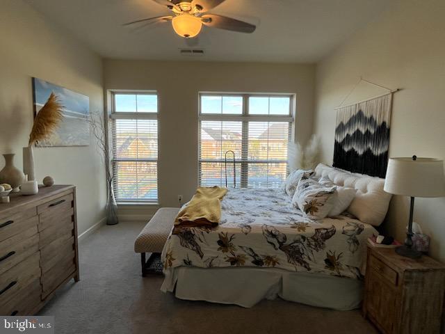 carpeted bedroom with baseboards, a ceiling fan, and visible vents
