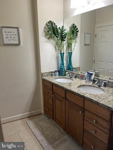 bathroom with baseboards, tile patterned flooring, a sink, and double vanity