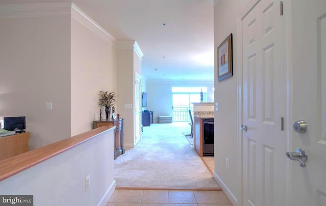 hall with baseboards, crown molding, light colored carpet, and light tile patterned floors