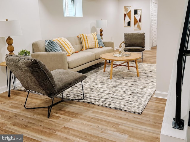 living area featuring baseboards and light wood finished floors