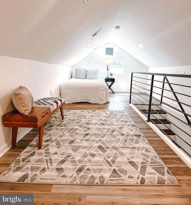 bedroom with wood finished floors, vaulted ceiling, and baseboards