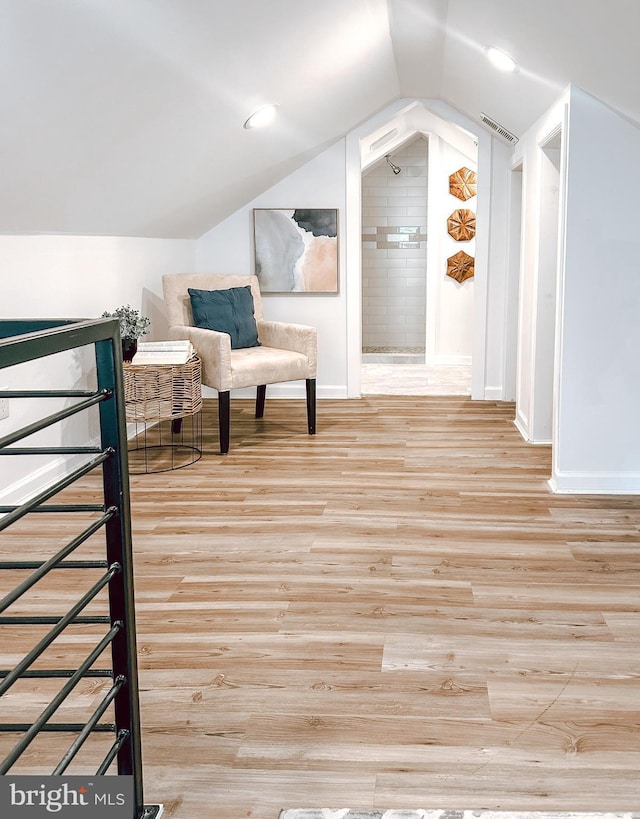 unfurnished room with wood finished floors, visible vents, vaulted ceiling, and baseboards
