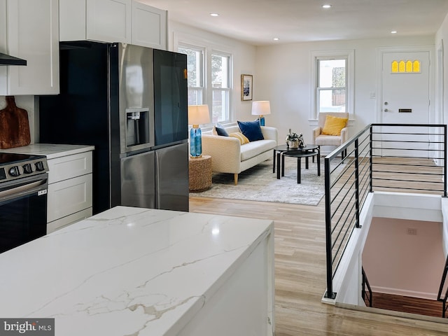 kitchen featuring electric stove, plenty of natural light, light wood finished floors, and refrigerator with ice dispenser