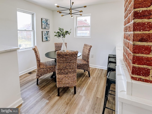 dining space featuring visible vents, a notable chandelier, baseboards, and light wood-type flooring