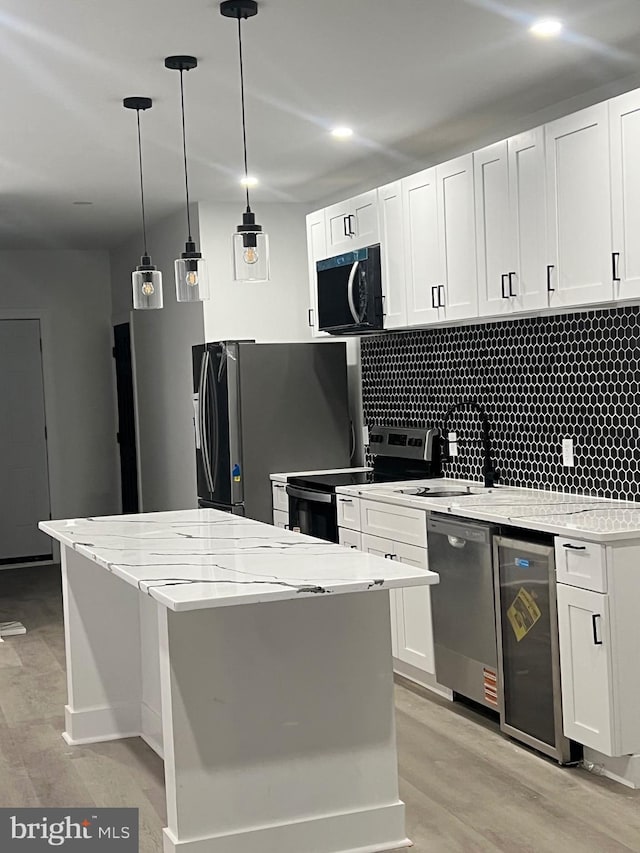 kitchen with decorative backsplash, a center island, light wood-style floors, stainless steel appliances, and white cabinetry